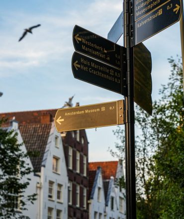 Street signs in Amsterdam pointing to local attractions including the Amsterdam Museum.